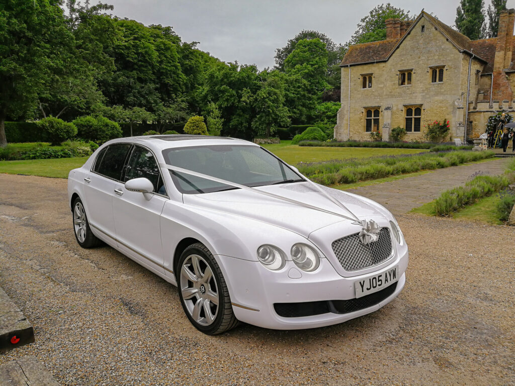 White Bentley Flying Spur Wedding Car parked in front of a luxury wedding venue