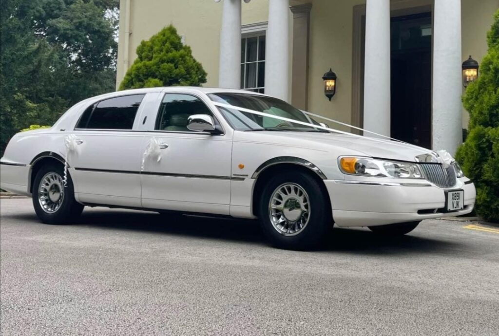 White Lincoln Town Car Cartier edition parked outside the front of an impressive wedding venue
